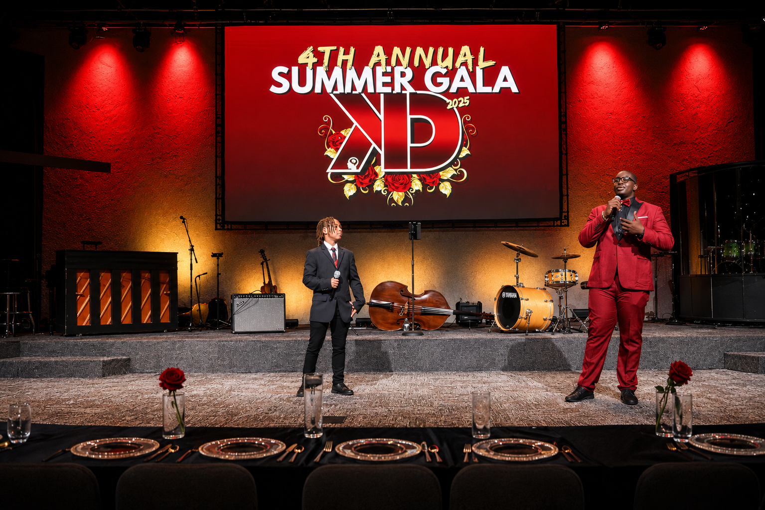 A young Kut Different mentee in a tailored tuxedo delivers his speech at the podium under warm stage light.
