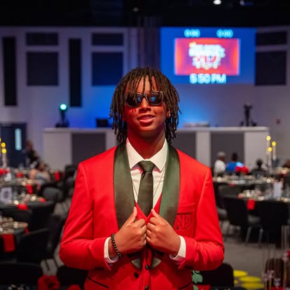 A young Kut Different mentee delivers his speech on stage in formal attire.